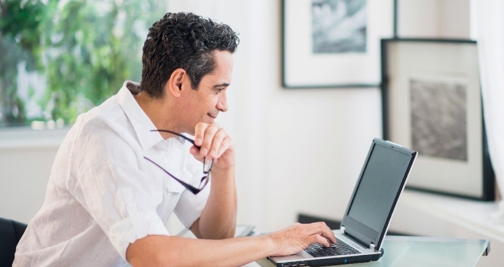 man smiling while browsing on a laptop