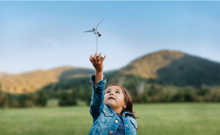 little girl holding up a windmill outside in a field