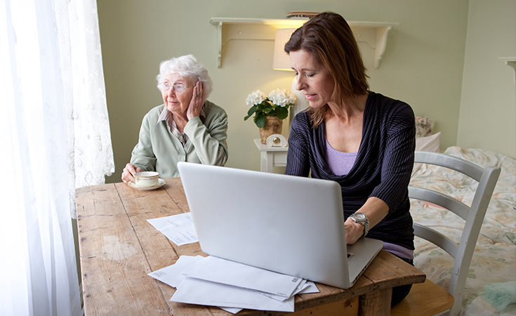 woman typing on laptop while sitting with elderly mother