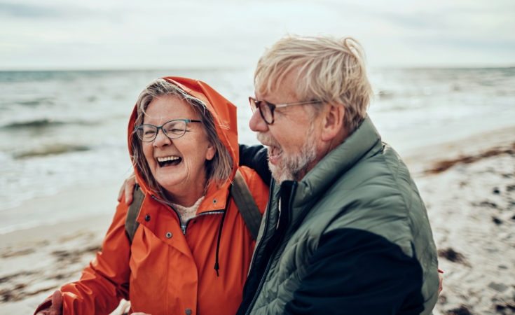 older white couple laughing on the beach
