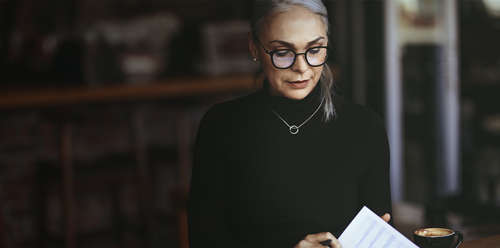 Woman seated alone concentrating on documents.