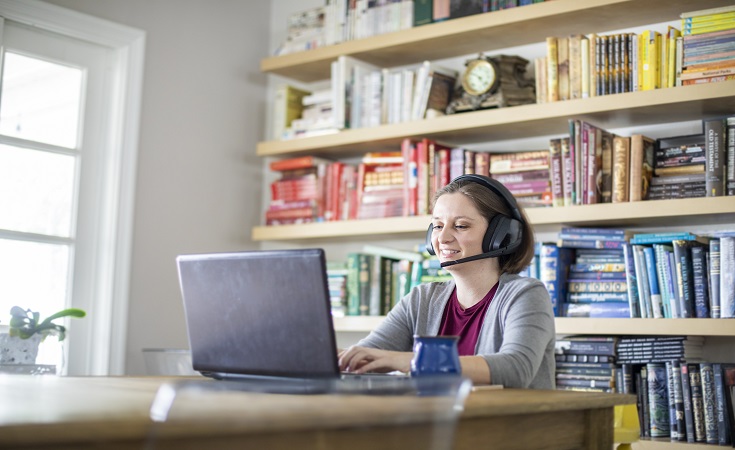 Woman sitting at a computer with headphones