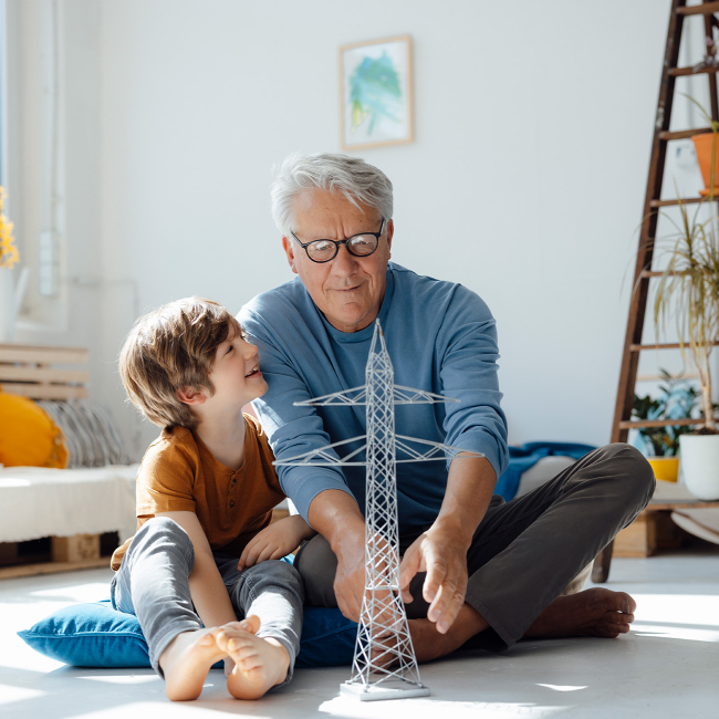 Grandparent and Child Building Metal Tower Model Indoors