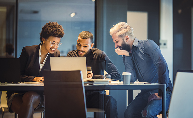 three financial professionals looking at a computer screen together