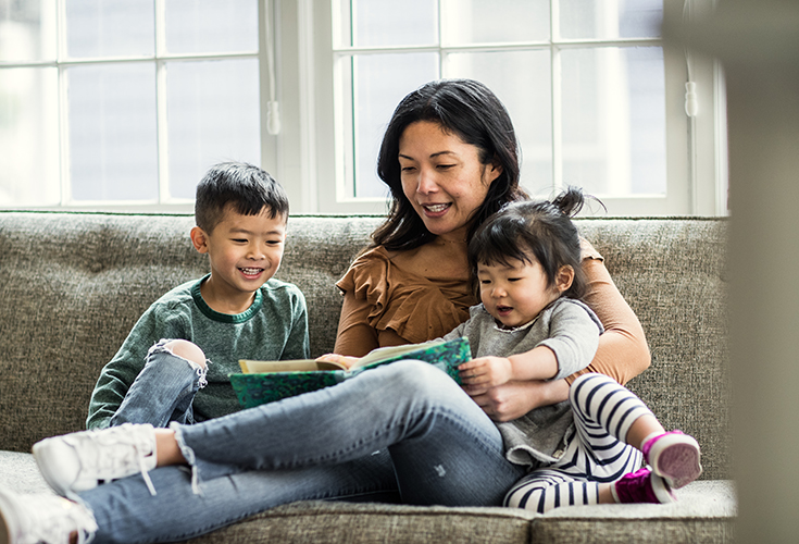 Mother reading to kids on couch