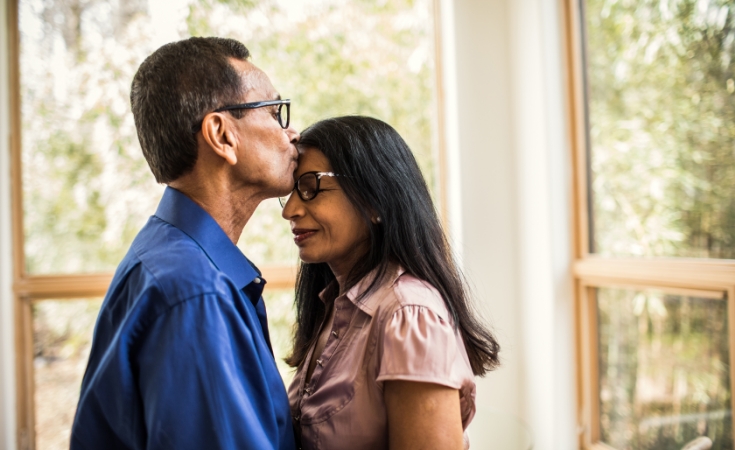 Mother and daughter smiling while looking at a tablet and sitting on a sofa