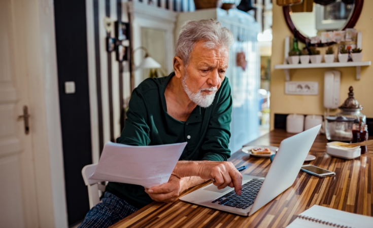 older man working on his laptop at home