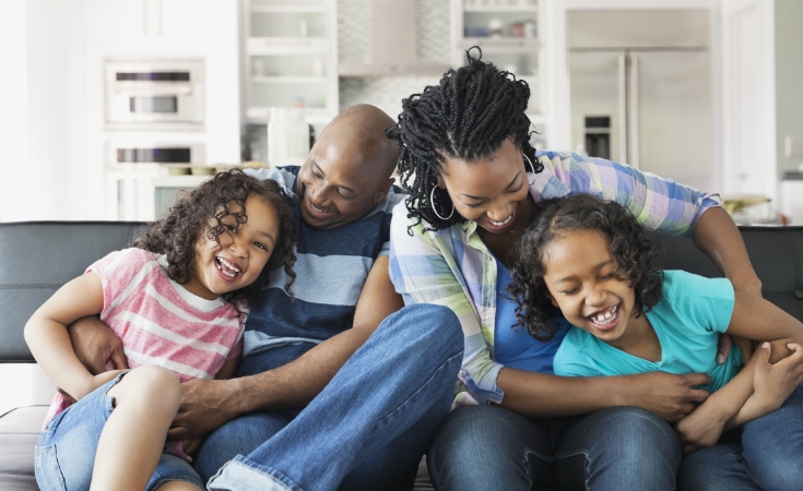 Family sitting on a sofa laughing