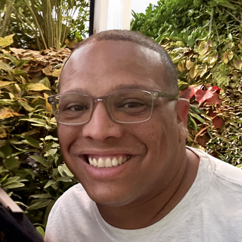 male educator smiling in front of trees