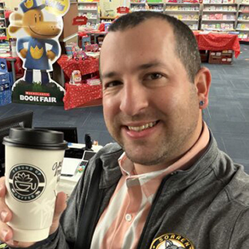 male educator smiling and holding a coffee