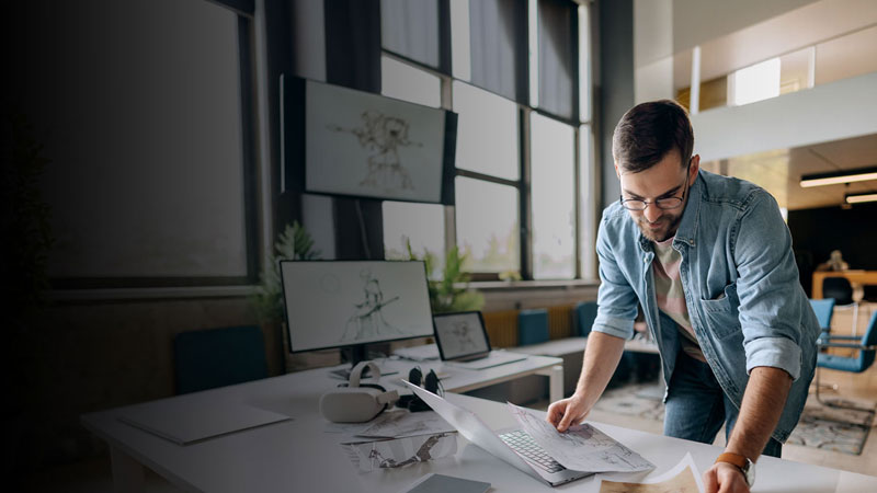 man looking at art sketches at a desk