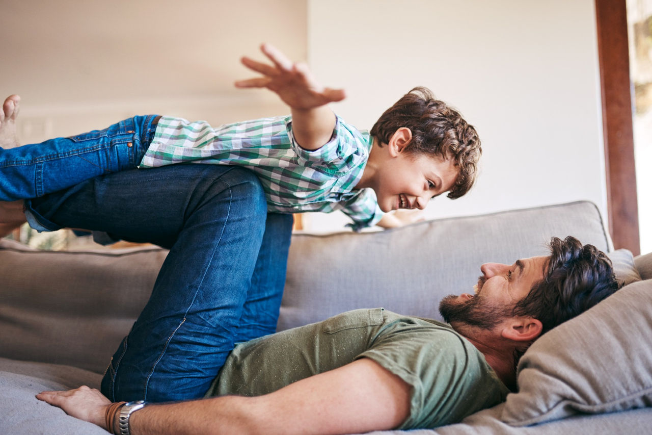 Dad playing with child on a sofa